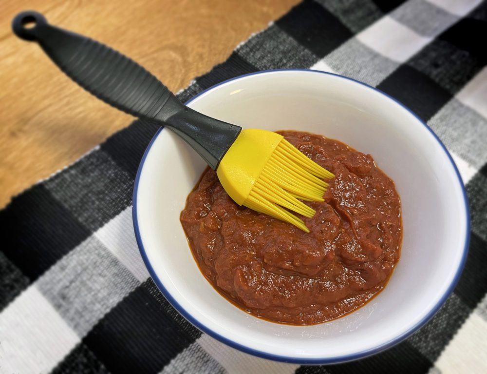dish of pizza sauce with a brush